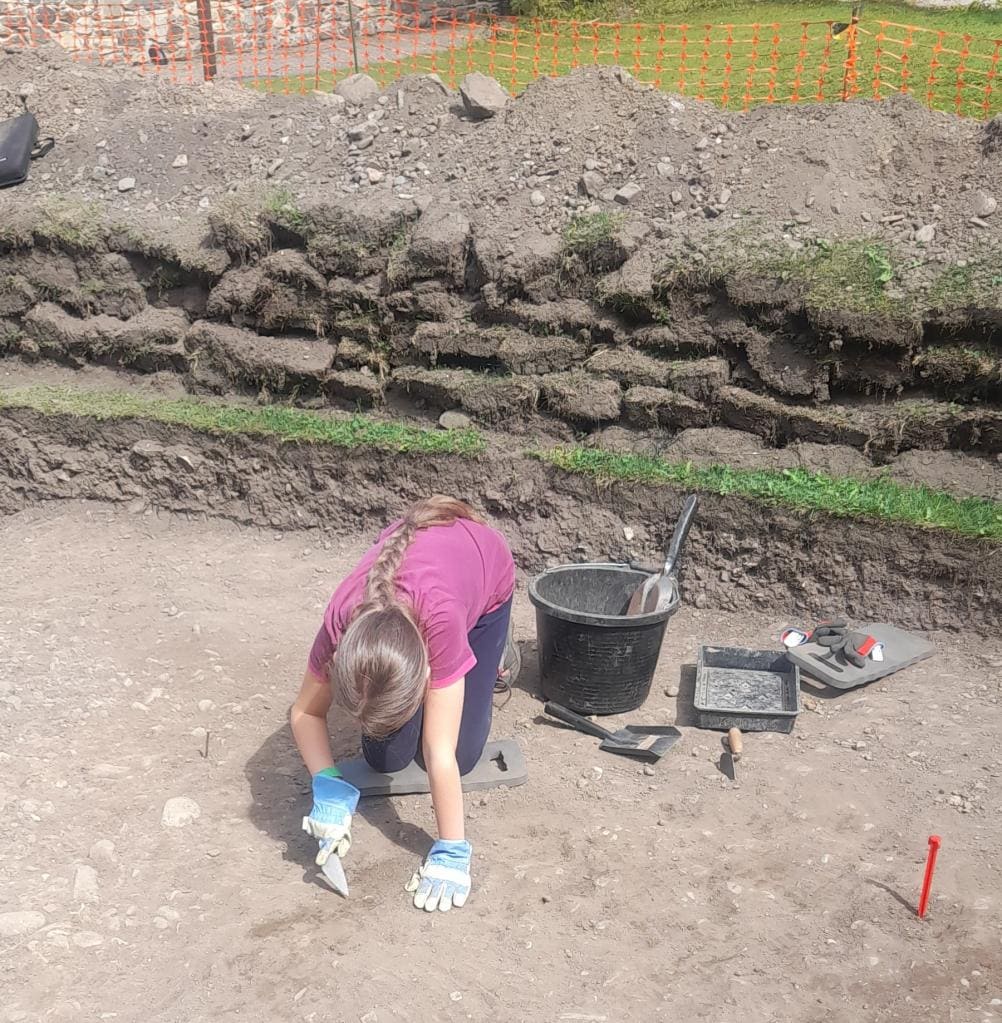 Liliwen digs in the trench next to excavation tools. 