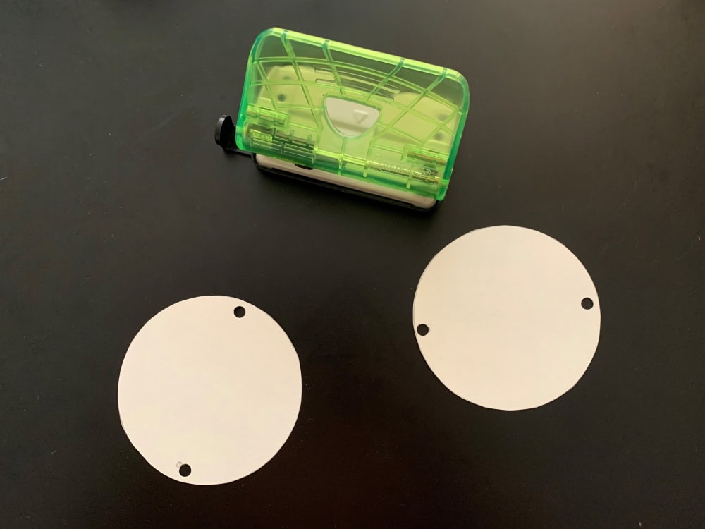 Two neatly cut out circles with two holes punched at both sides of each circle.
