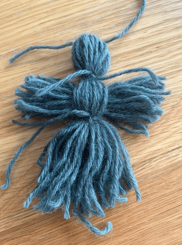 Yarn is tied to secure the doll's arms and create it's waist.