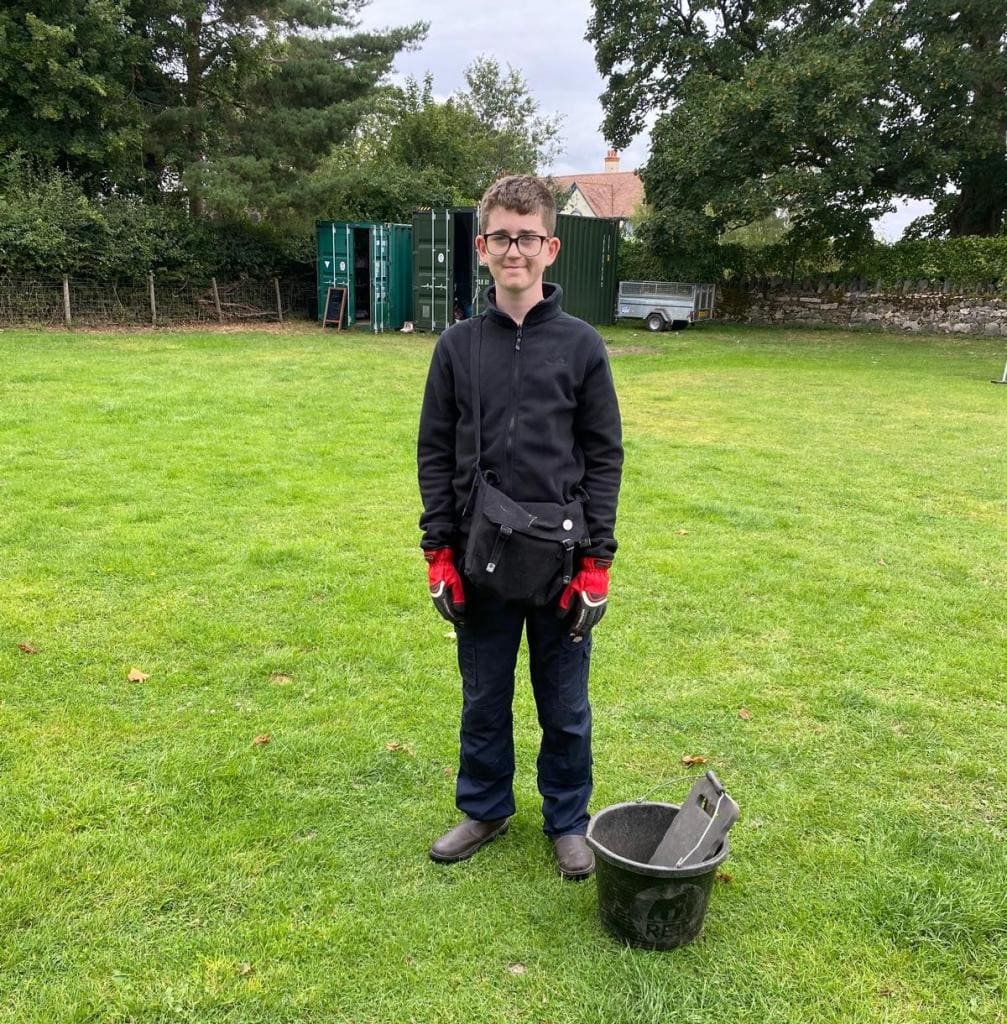 David stands next to a bucket. 