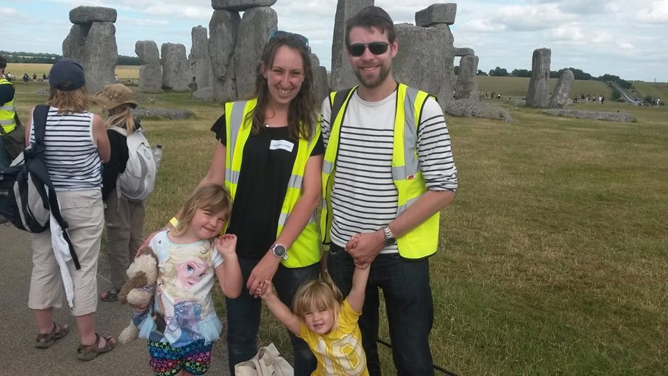 A man and woman and two young children stand in front of Stone Henge.