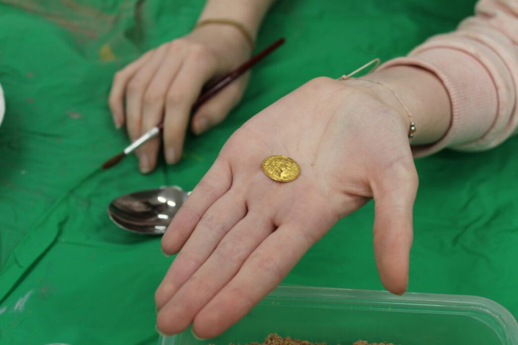 A close-up of a gold-coin in a person's hand.