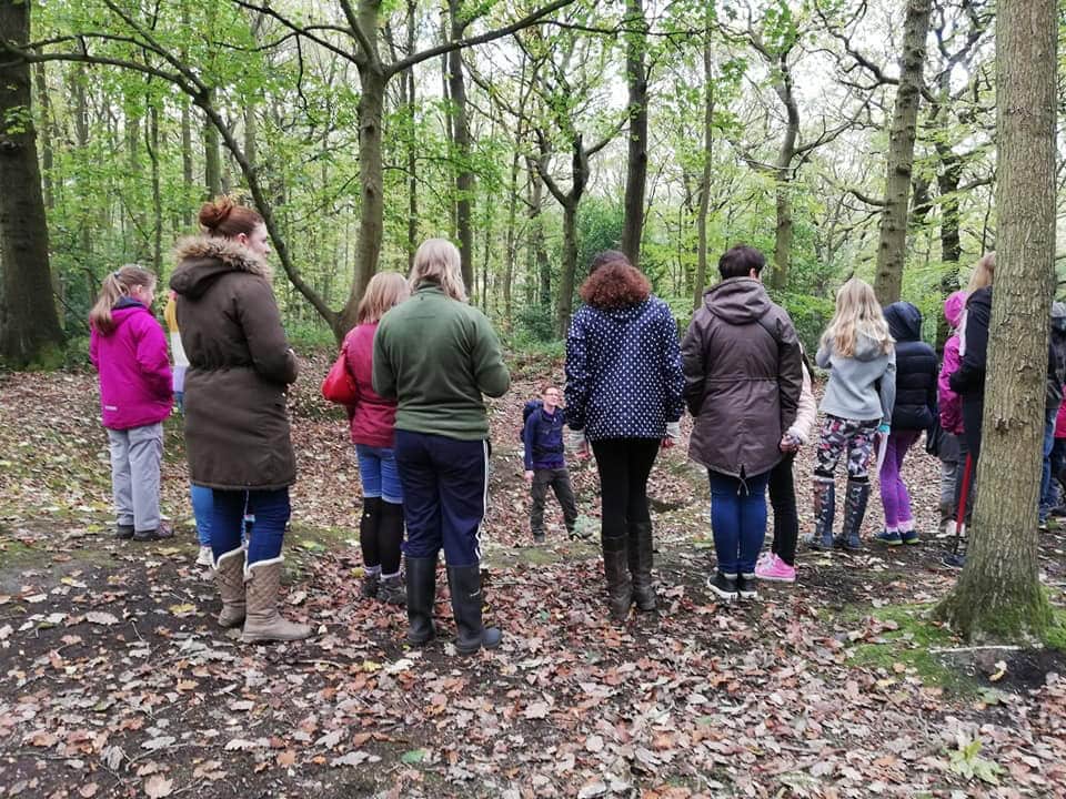 A group of young people and adults standing in a forest.
