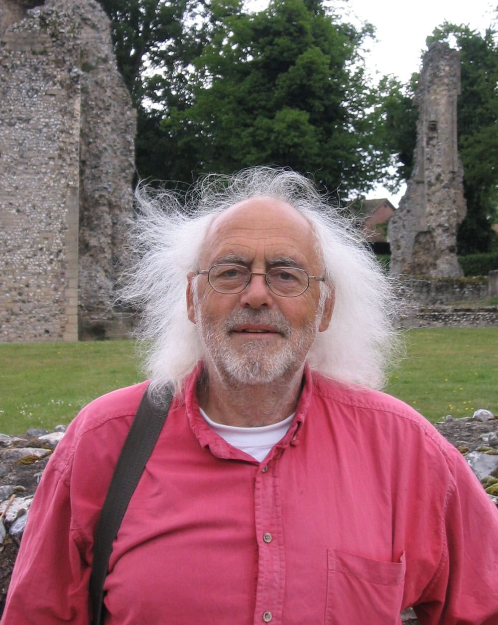 A man standing outside; historic abbey ruins in the background.
