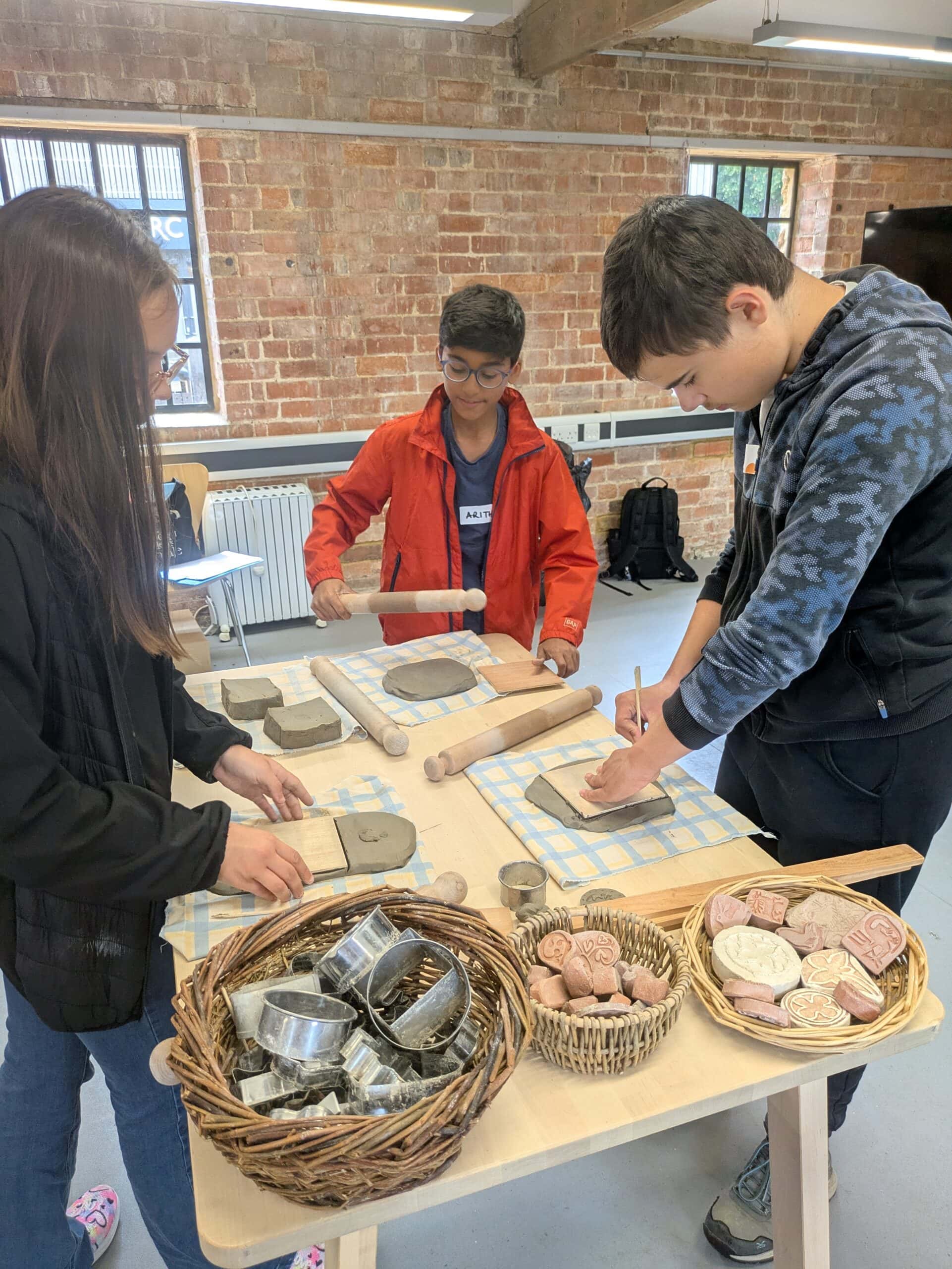 A group of 3 stand around a table looking at different archaeological artefacts