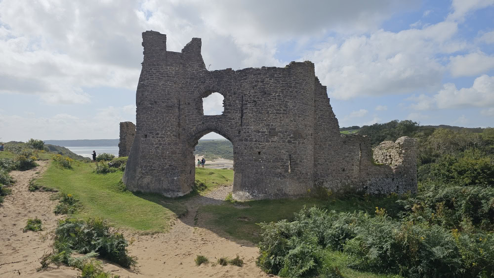 A stone castle ruin in a coastal landscape.