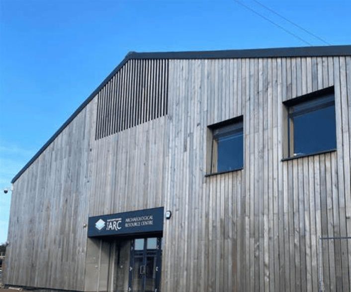 A large modern wooden building with a sign reading 'ARC: Archaeological Resource Centre'.