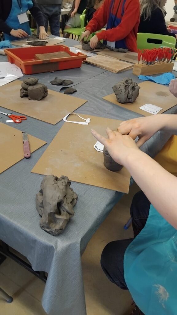 Young people sat around a table shaping lumps of clay.