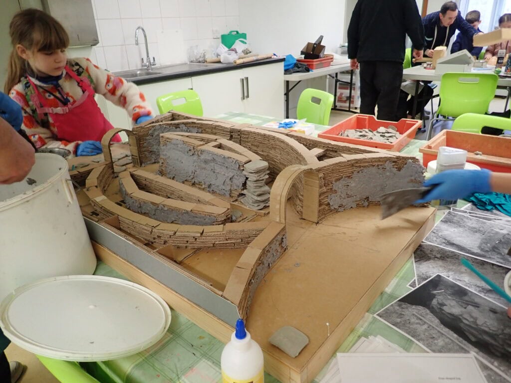 Young people arranging a structure made from cardboard on top of a table