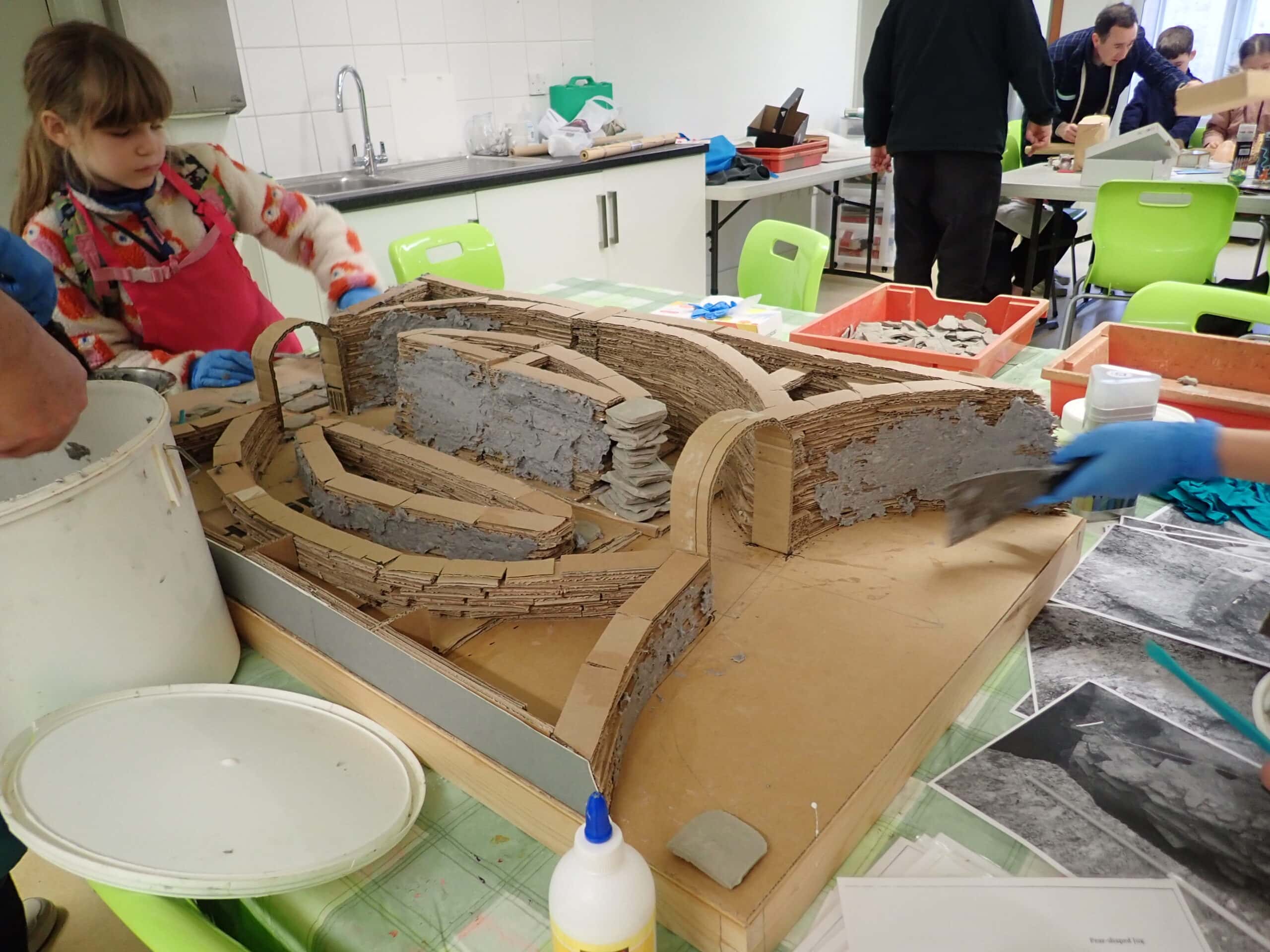 Young people arranging a structure made from cardboard on top of a table