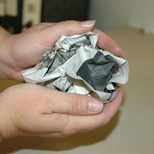 Someone demonstrates scrunching newspaper into a ball to form the base of the petrosphere craft.