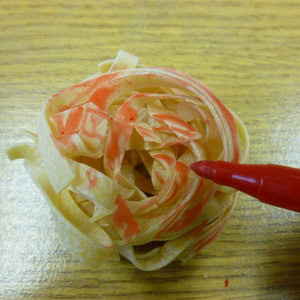 Dried pasta being coloured in red to make mock organs.