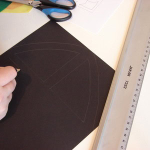 Drawing the stained glass frame outline design onto black card with a pencil.