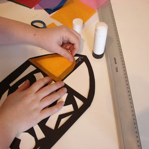 Sticking yellow tissue paper onto the stained glass paper outline.