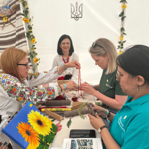Four people craft the dolls together at a table.