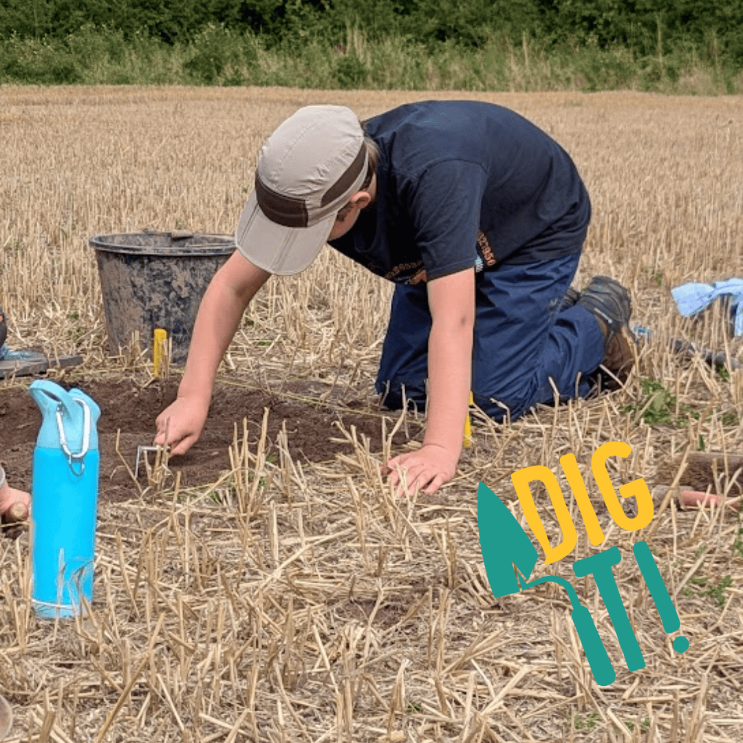A young person kneels in an archaeological trench and scrapes the soil with a trowel.
