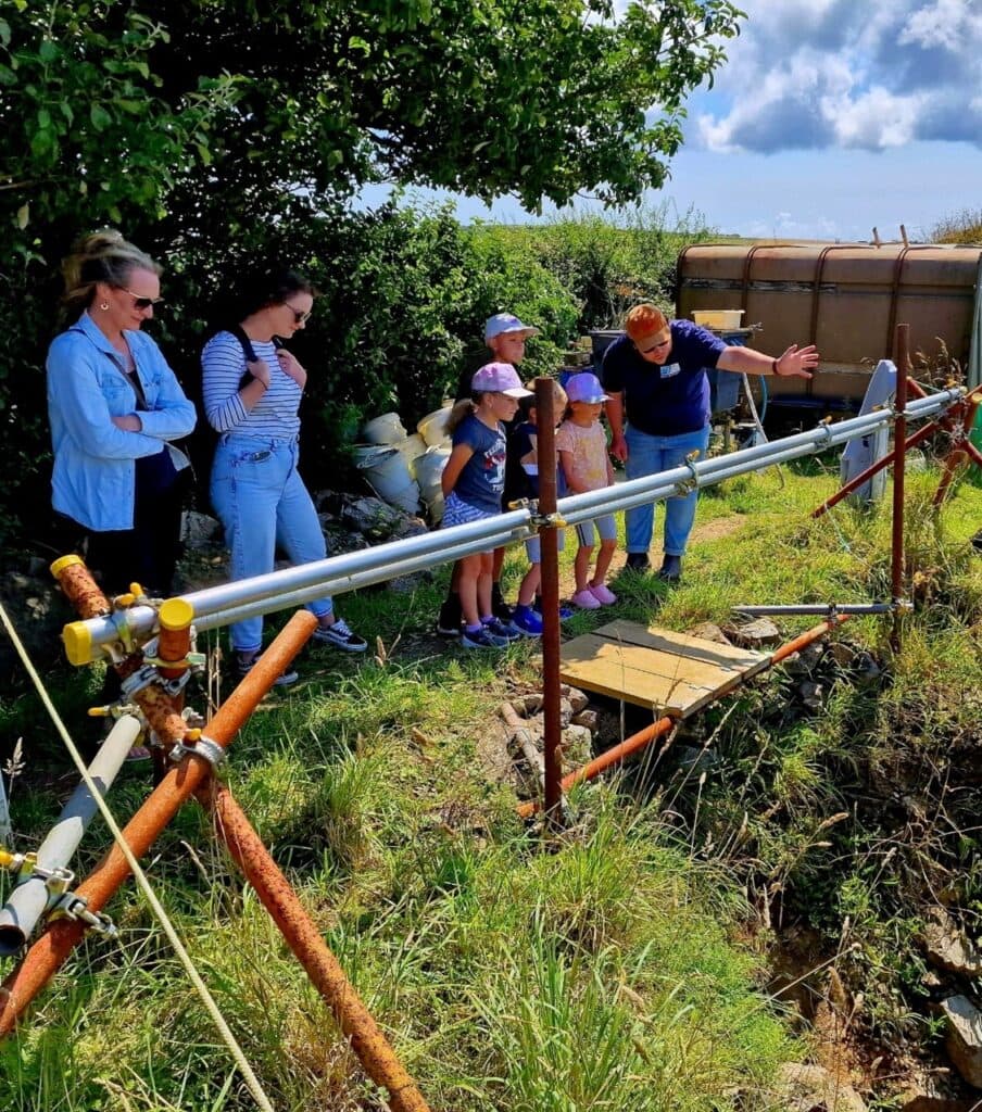 A group of adults and young people watching an archaeological dig