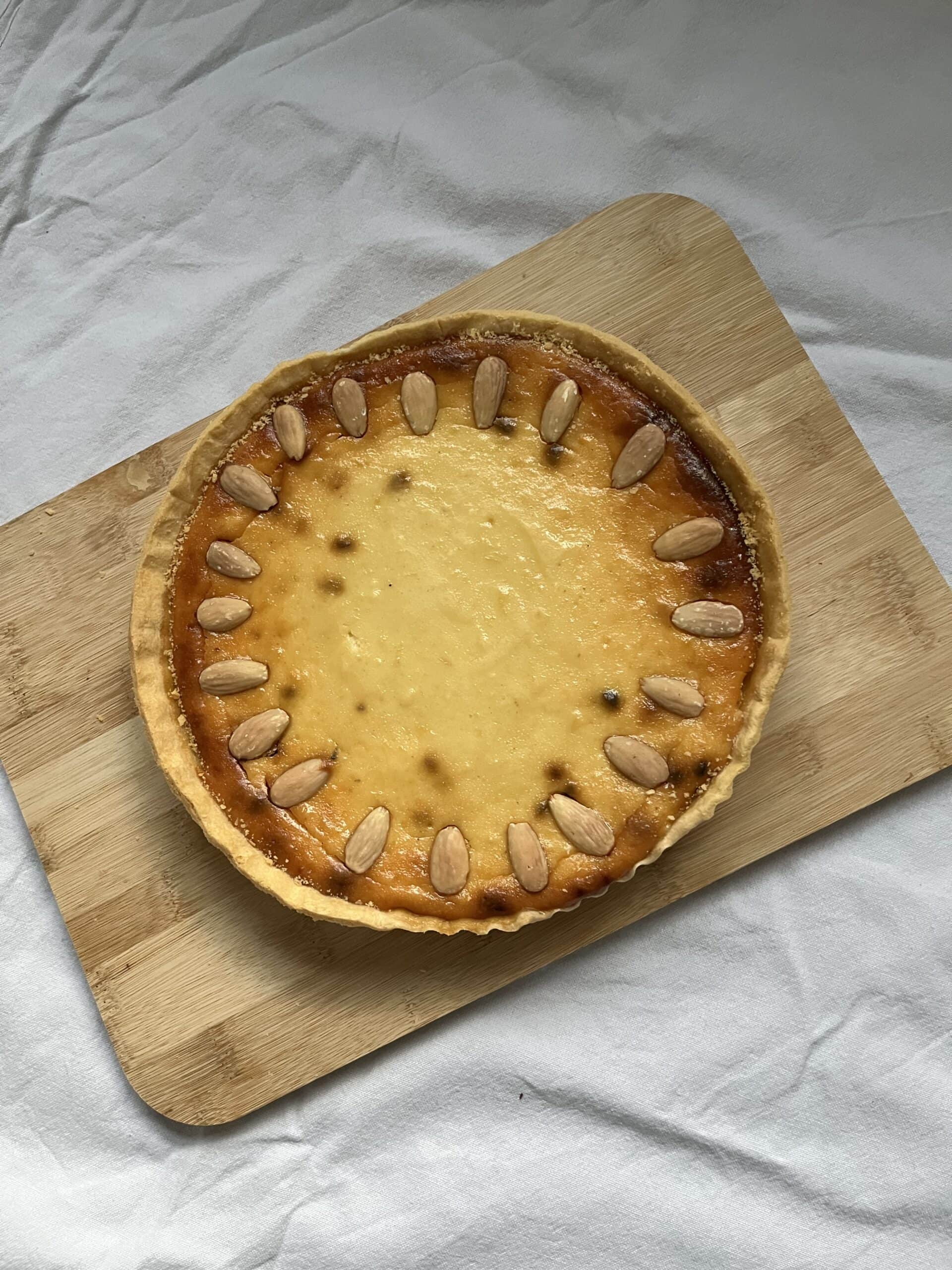 A cheesecake-style tart in a short crust pastry case, decorated with almonds.