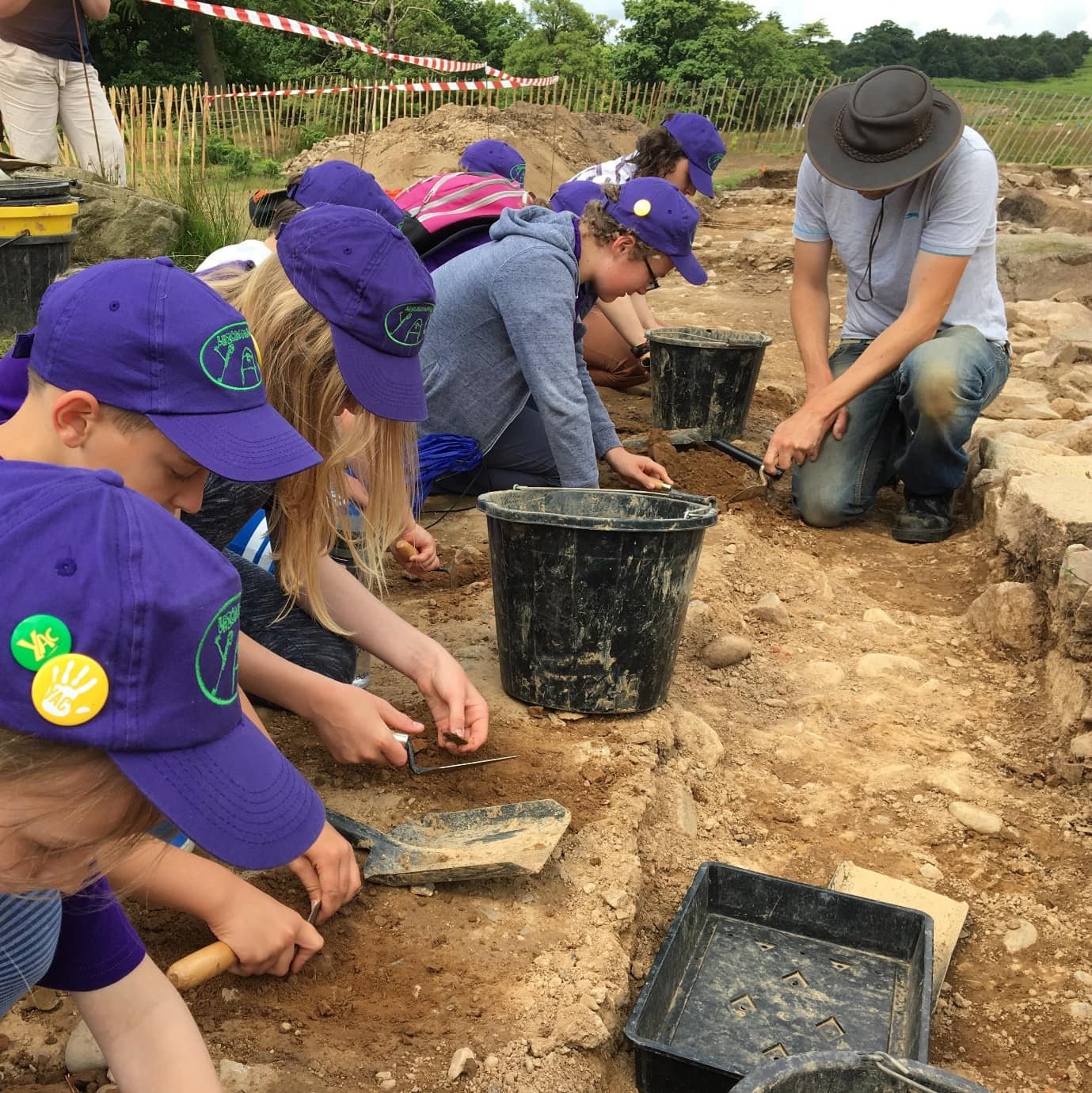 A group of young people digging on an archaeological excavation.