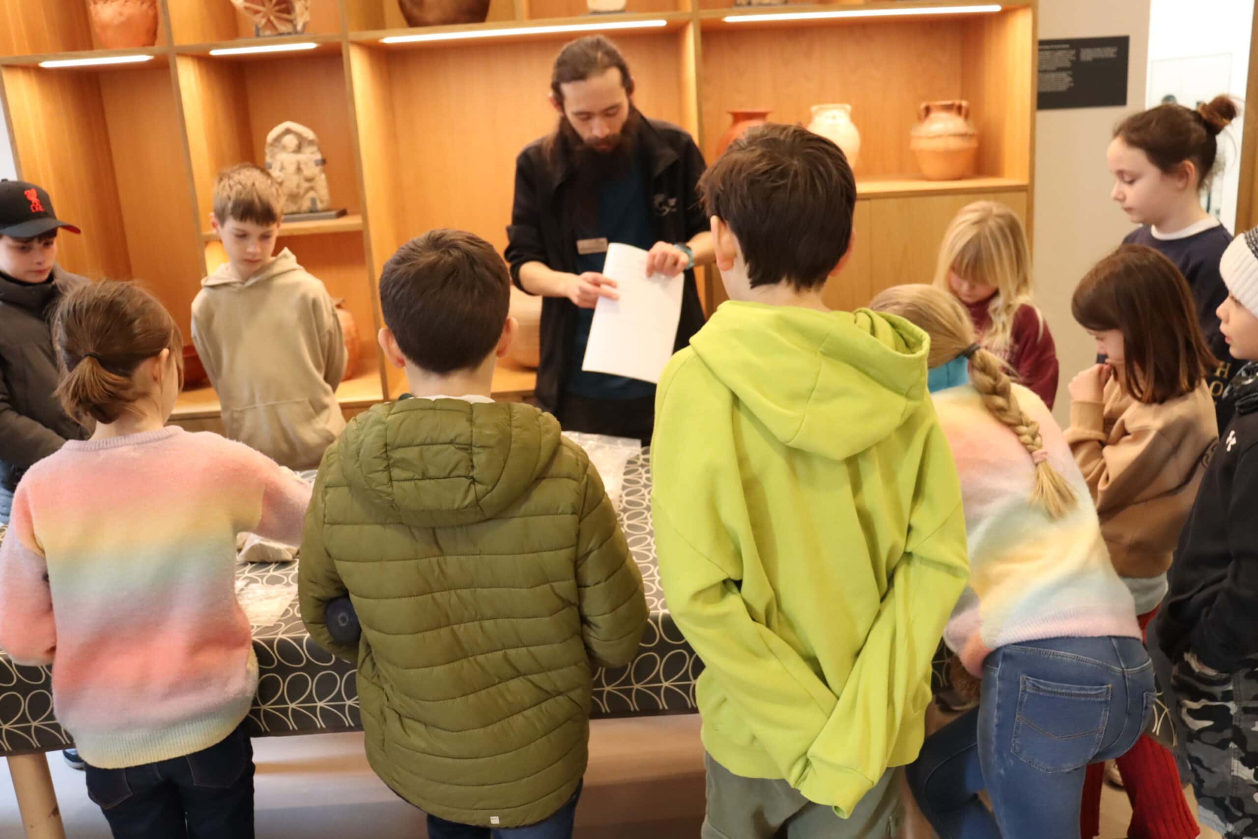 A group of children stand around a table in a museum