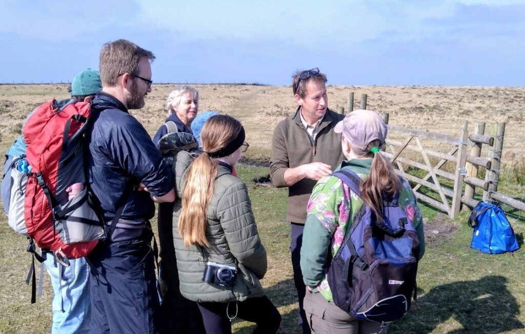 A group of adults and children in a field on a sunny day.