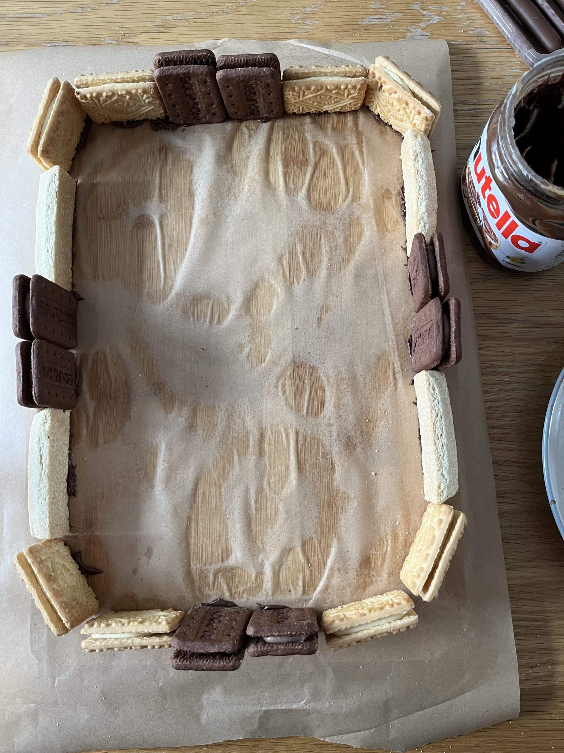 Biscuits arranged in a rectangular shape next to a jar of chocolate spread