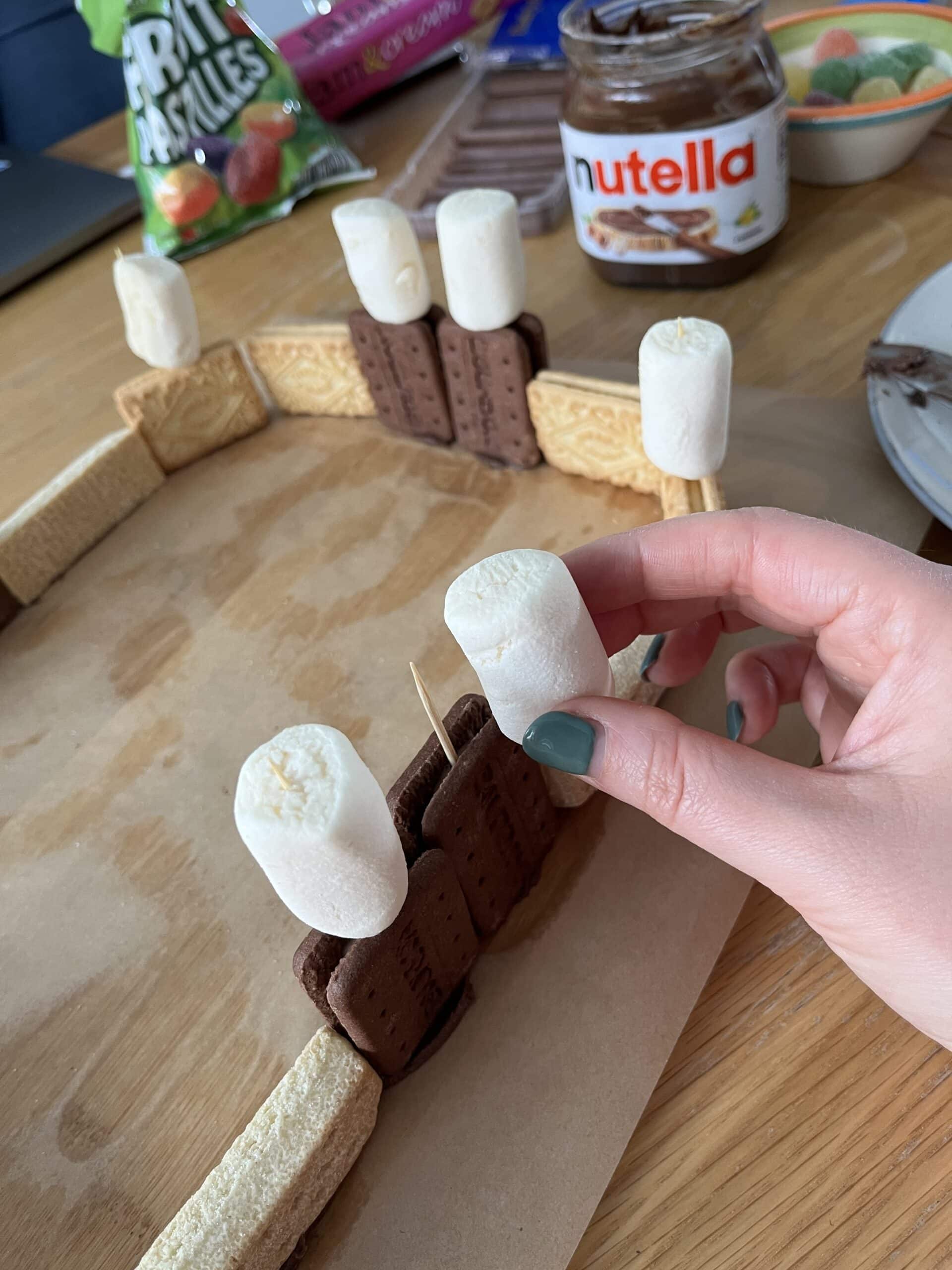 Large white marshmallows attached with cocktail sticks to the filling of sandwich biscuits, arranged in a rectangular shape to represent a fort.
