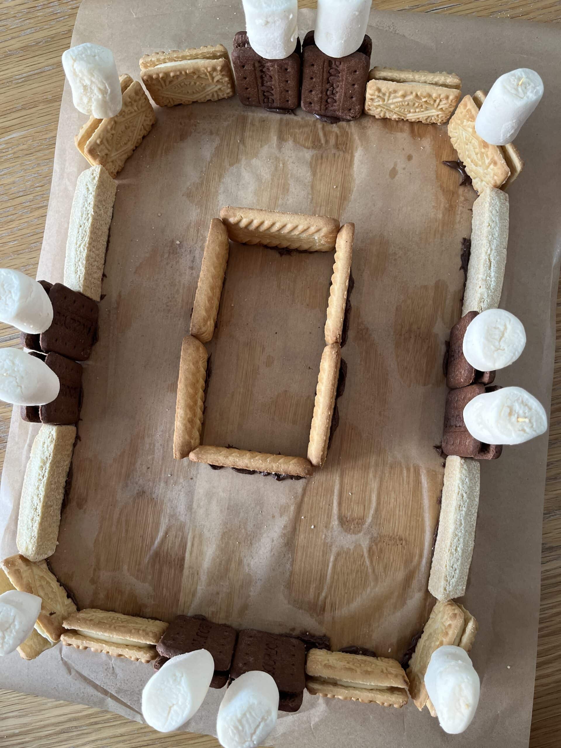 A rectangular structure made from biscuits and marshmallows, with a smaller rectangular structure in the centre.
