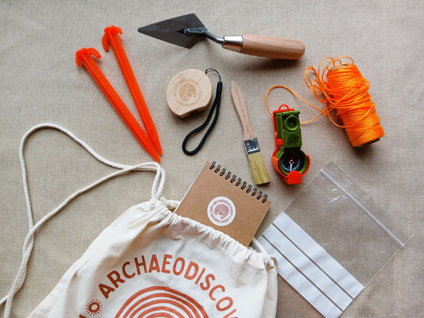 A selection of archaeological tools such as a trowel, brush and compass in a canvas bag.
