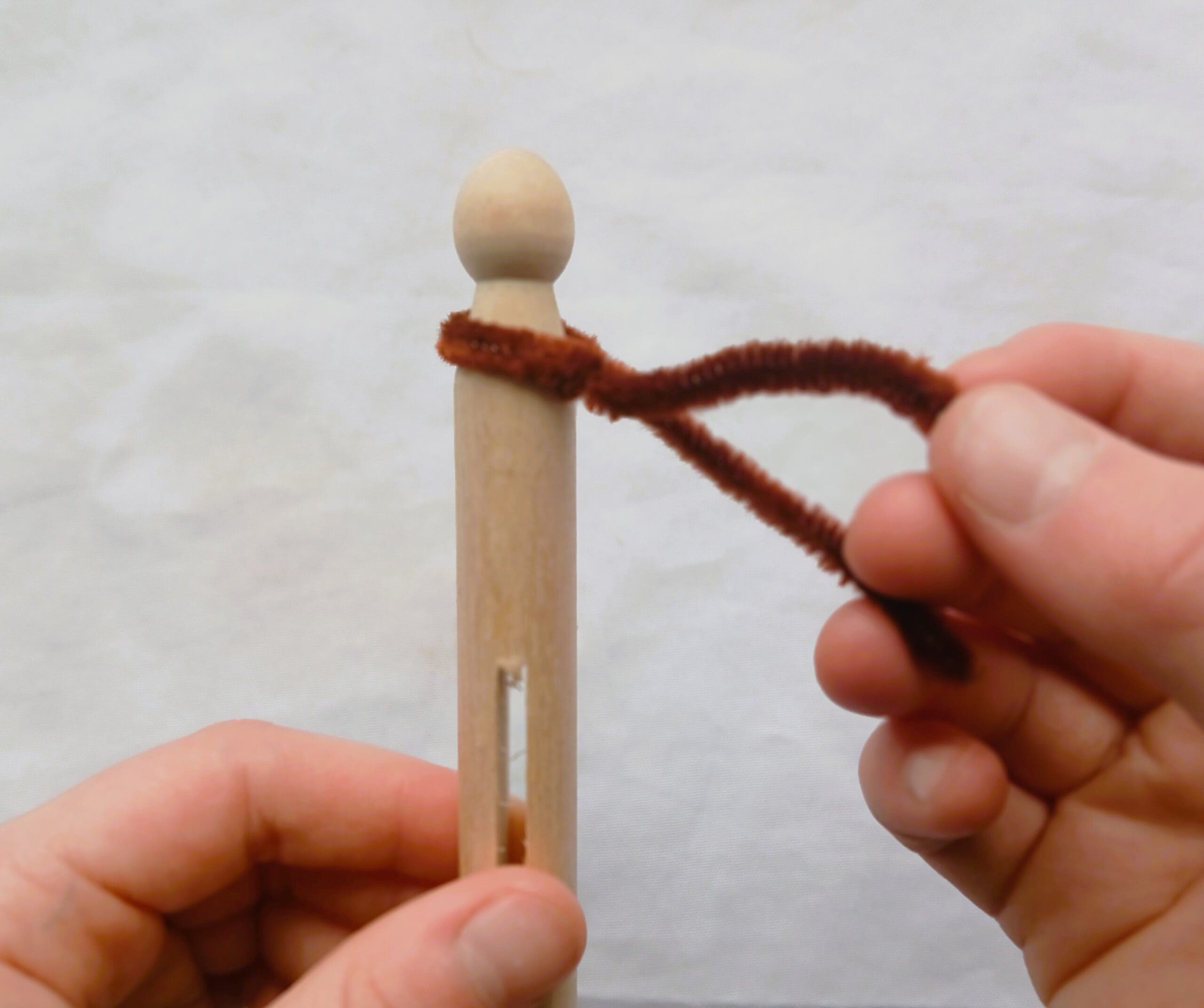 A wooden clothes peg with a brown pipe cleaner wrapped around it.