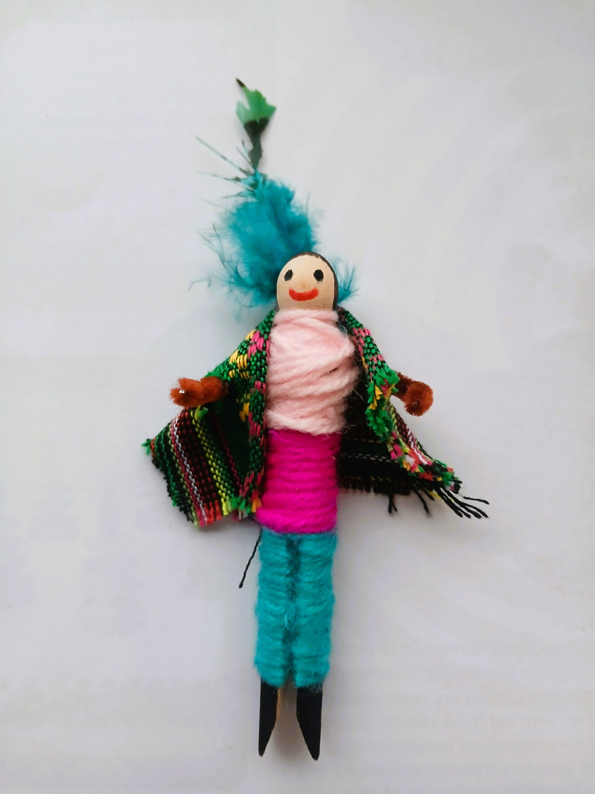 A small doll made from a peg wearing colourful Maya-inspired fabric.