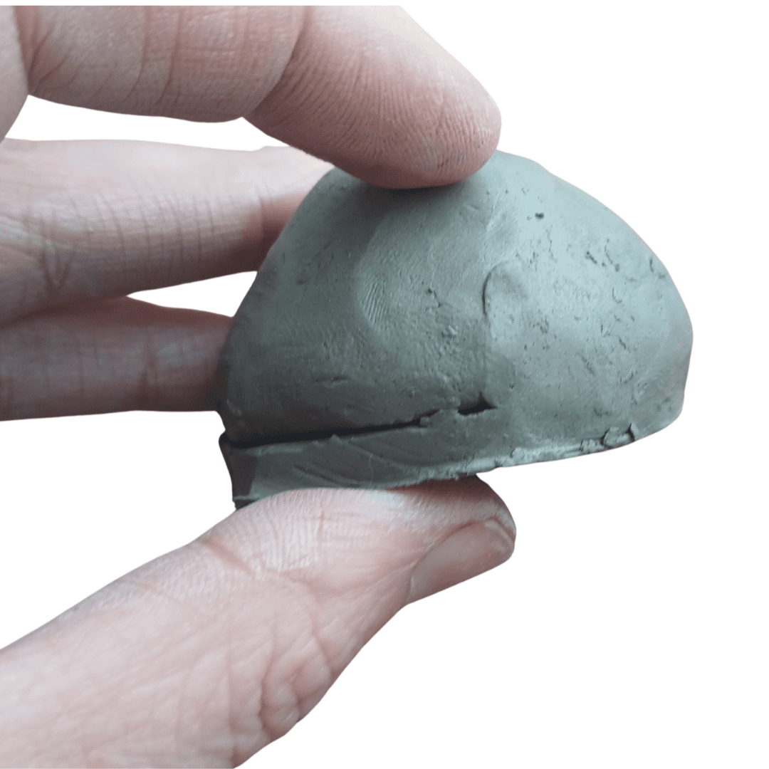 A hand holding a small clay bowl with a clay lid.