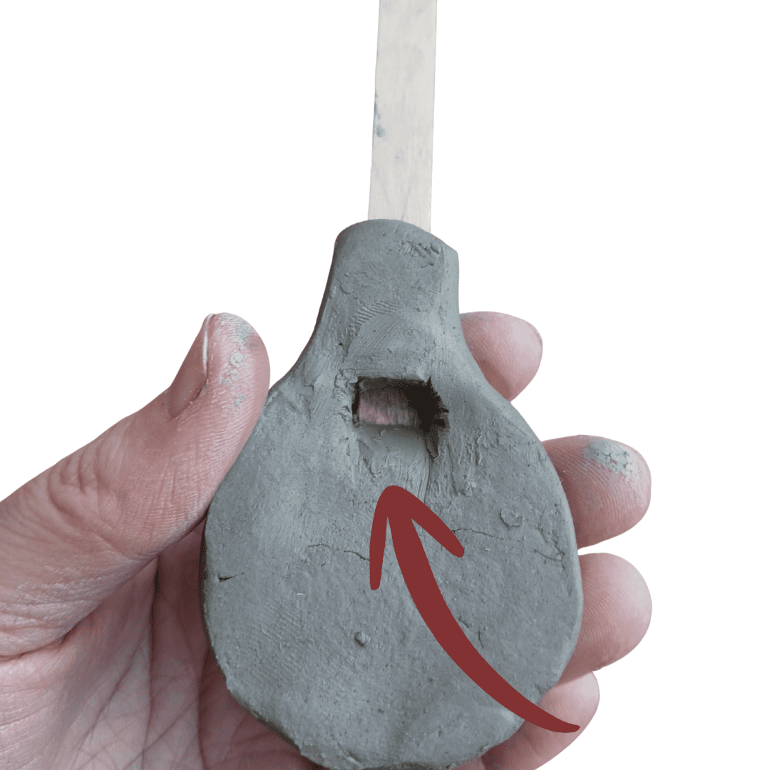 The underside of a round whistle made from clay.