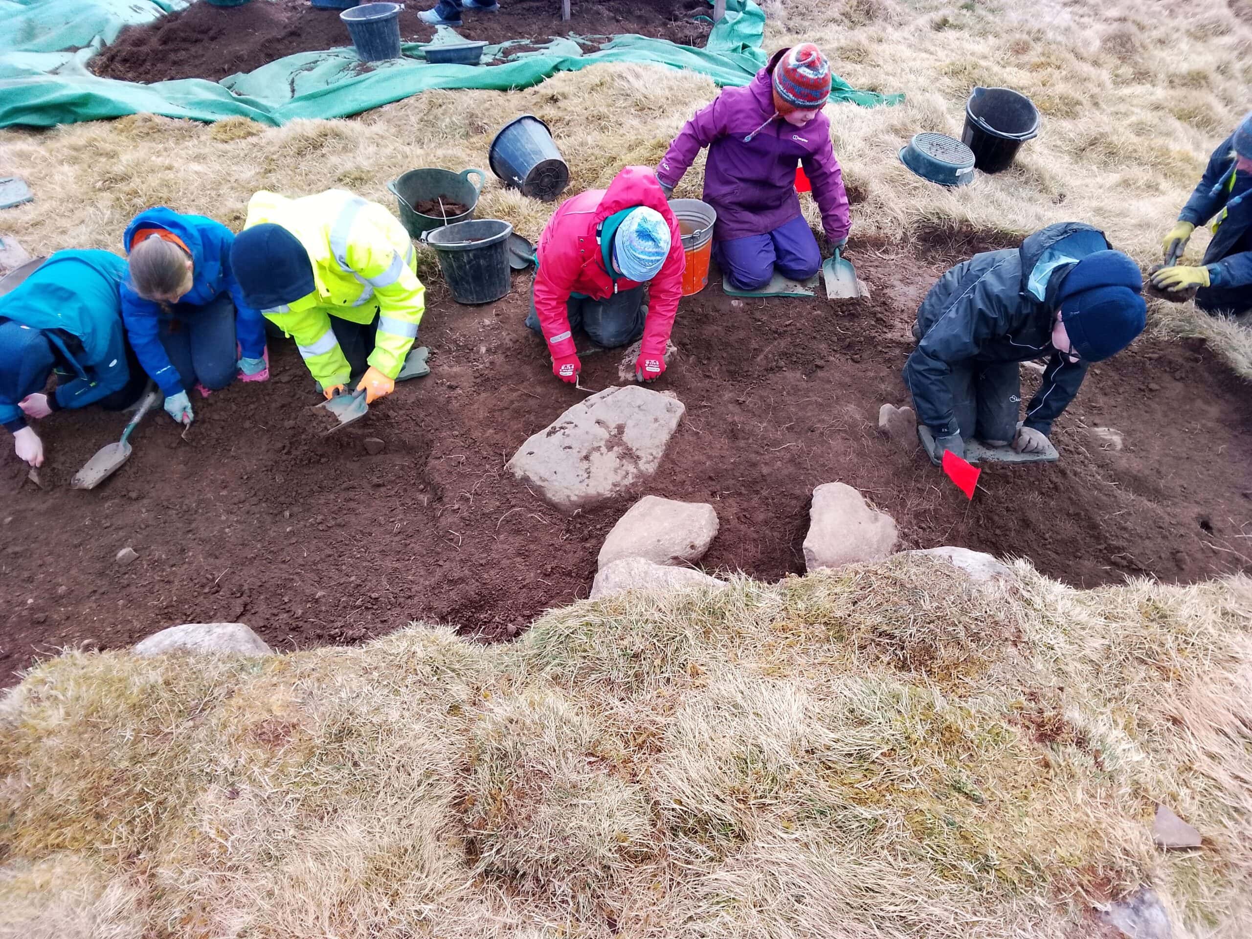 Six young people digging in a pit on an archaeological dig