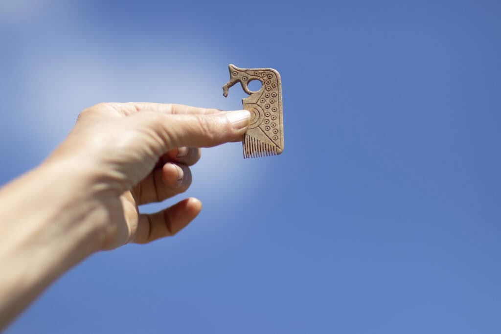 A person holds up a small early medieval comb