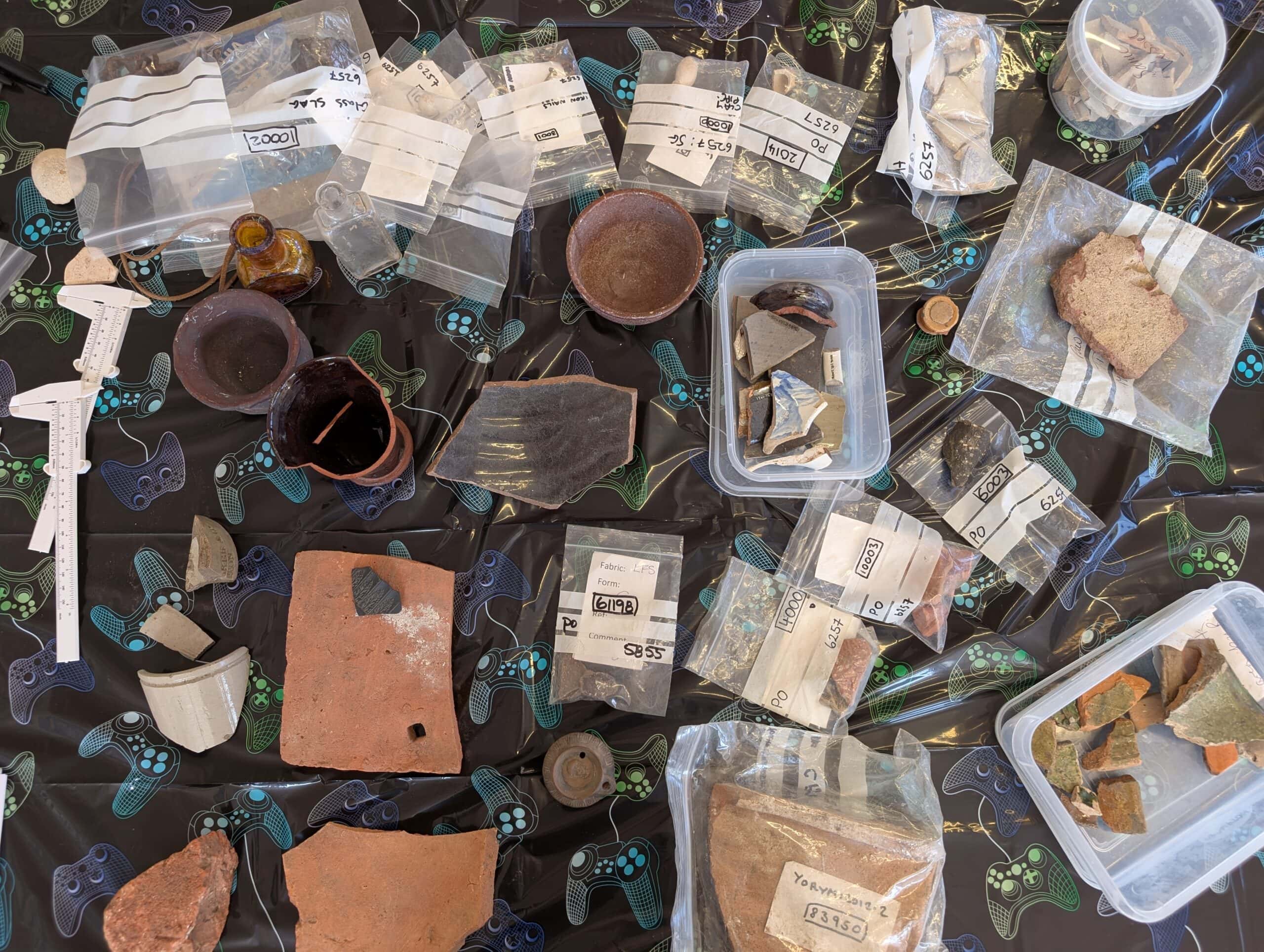 An assortment of pottery on a table in plastic boxes and on bags.