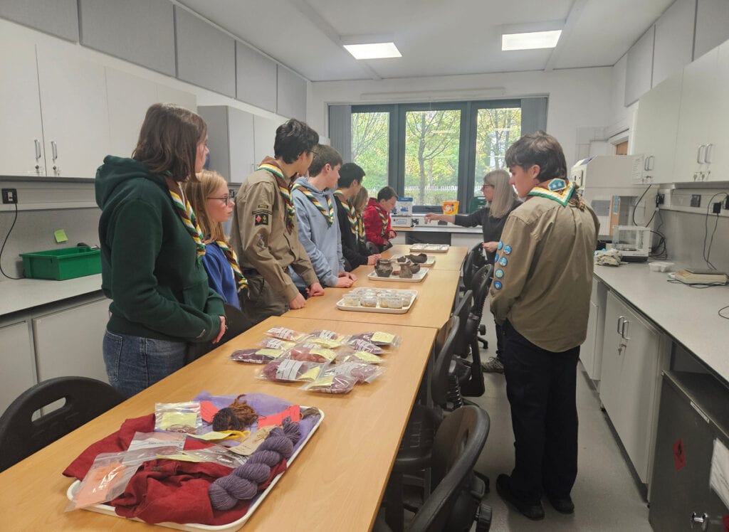 Scouts stood along a long wooden table in kitchen looking at materials related to the viking period on trays