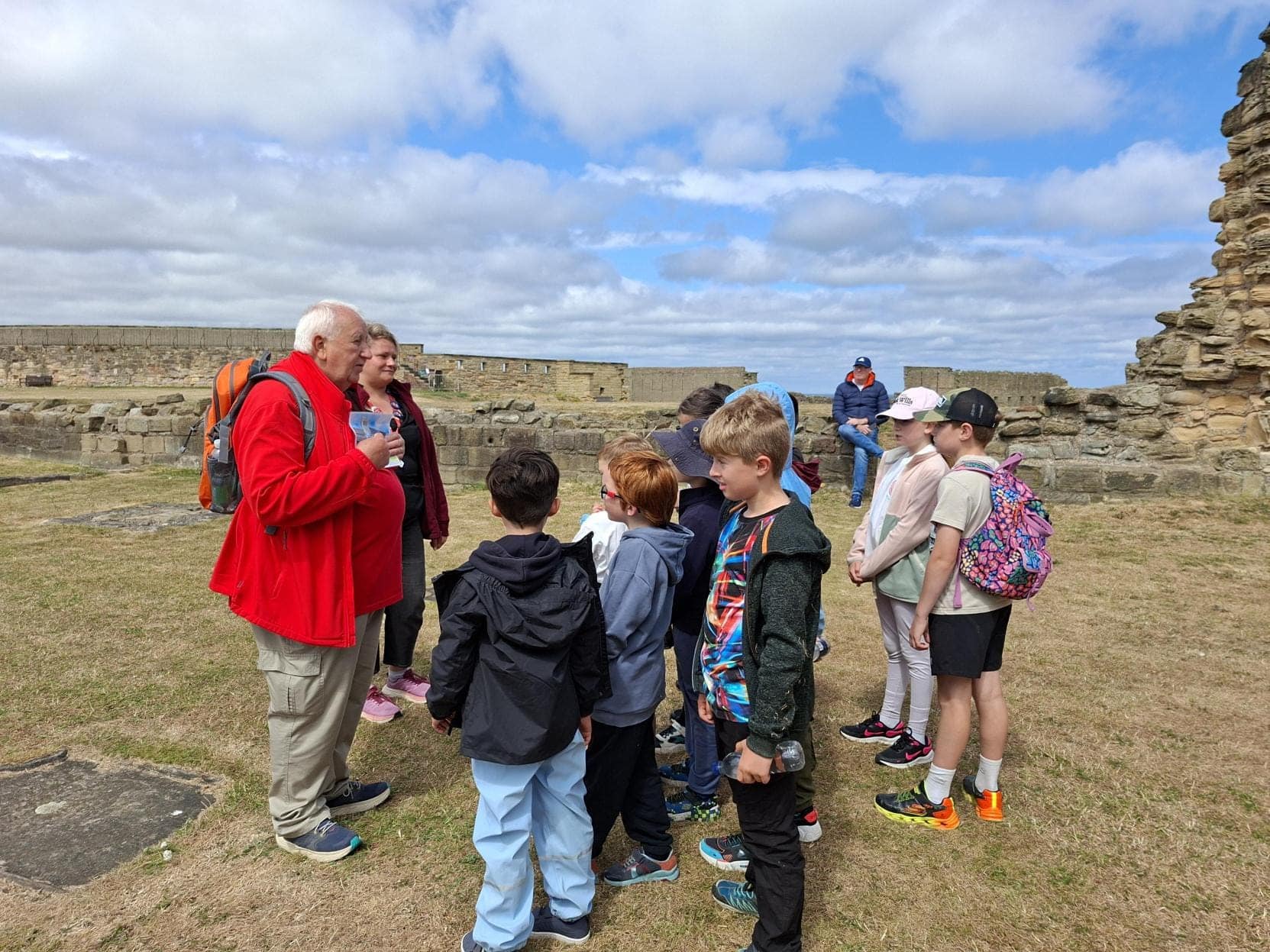 Image of a group of children listening to an adult in red jacket