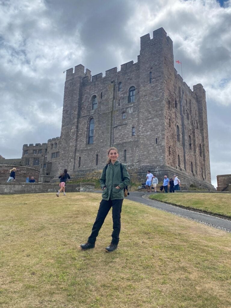 A young person stood in front of a medieval castle