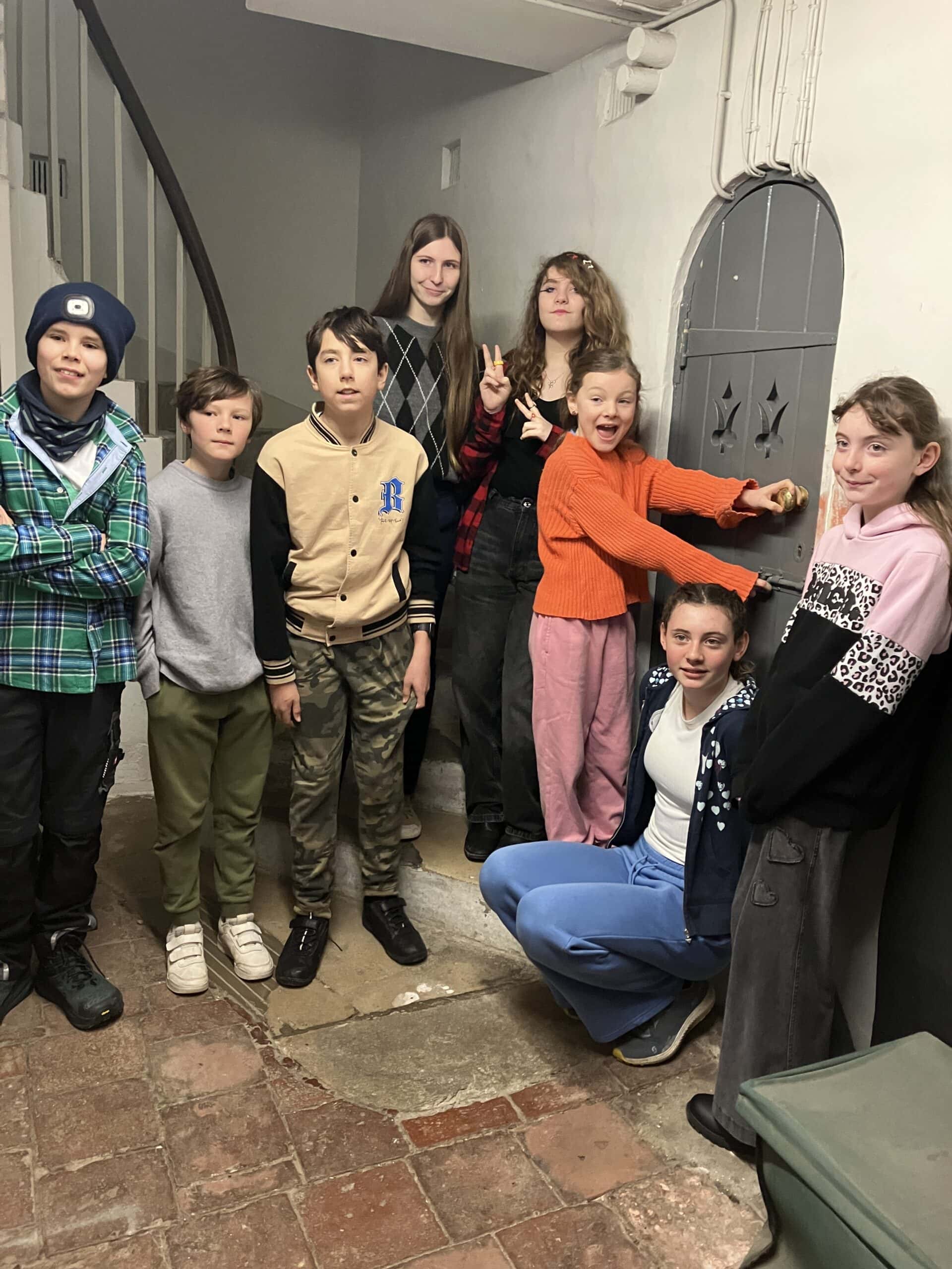 Eight young people gathered around an old door in an historic museum.